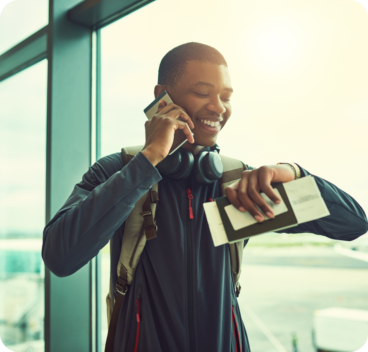african man on the phone holding passport and ticket
